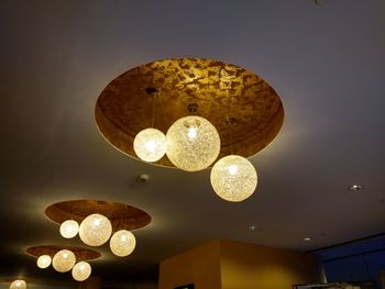 Low angle view of illuminated lighting equipment hanging on ceiling