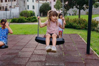 Three children playing with swings in public park