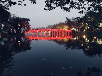 Illuminated bridge over lake against sky at night