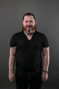 Portrait of mature man standing against black background