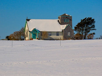 House on field against clear sky during winter