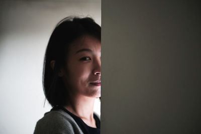 Portrait of young woman against wall