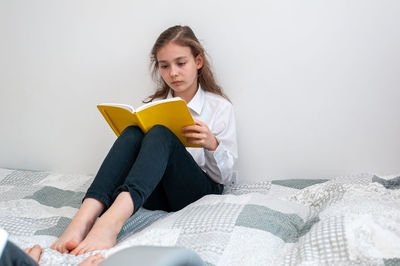 School age girl sitting in her bedroom and doing school homework.