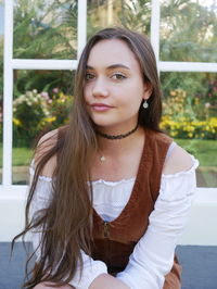 Close-up portrait of young woman against trees