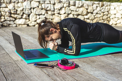 Woman exercising by laptop on floor