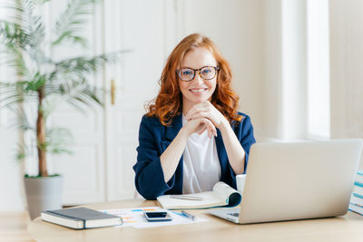 Portrait of smiling businesswoman sitting at desk in office