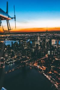 Aerial view of illuminated city against sky during sunset