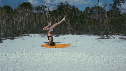 Full length of woman exercising at beach