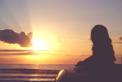 Rear view of silhouette woman at beach during sunset