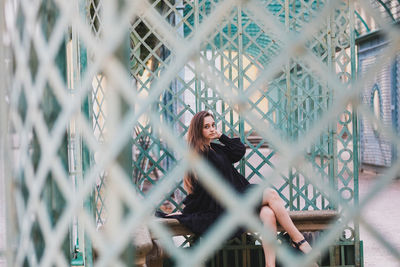Portrait of woman seen through metal gate