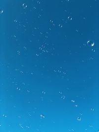 Low angle view of bubbles against blue sky