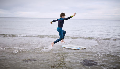 Full length of man surfing in sea against sky