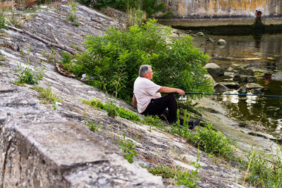 Rear view of man on rock by lake