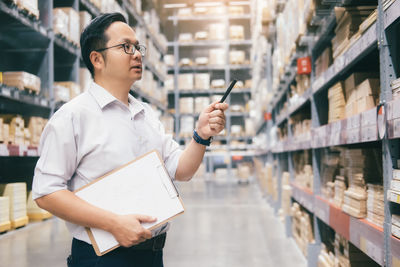 Midsection of man holding camera while standing in office