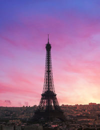 Communications tower in city against sky during sunset