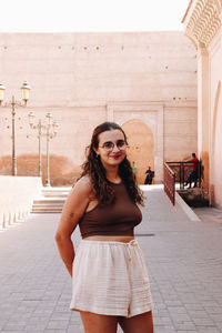 Portrait of young woman standing against building