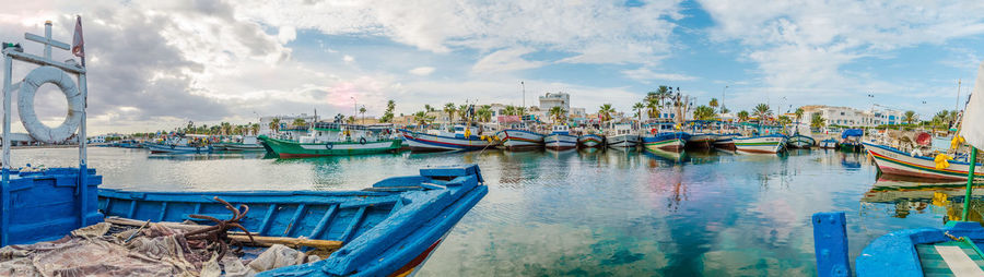 Panoramic view of boats moored in harbor against cloudy sky