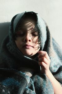 Close-up of girl with eyes closed wrapped in blanket