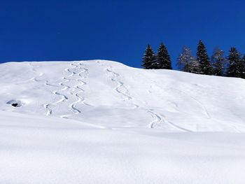 Snow covered landscape against blue sky