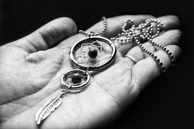 Cropped hand holding jewelry on hand against black background