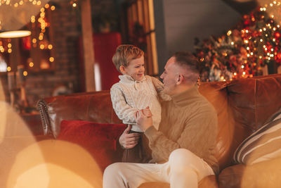 Candid authentic happy dad playing with little son fooling around at wooden lodge xmas decorated