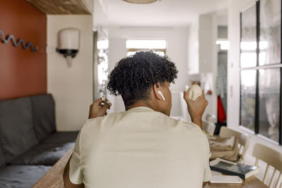 Rear view of teenage boy sitting in living room