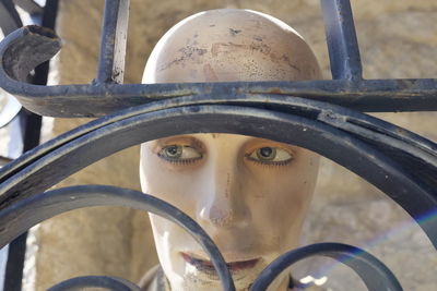 Close-up of mannequin seen through metallic fence