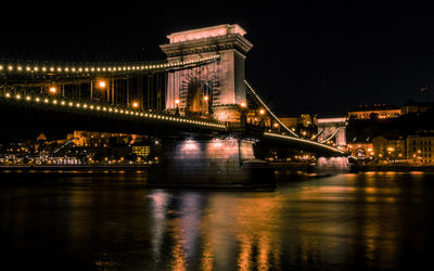 Illuminated bridge over river at night