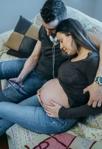 High angle view of couple looking at digital tablet while sitting on sofa at home