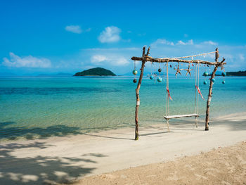 Scenic white sand beach, swing and turquoise sea against blue sky. koh mak island, trat, thailand.