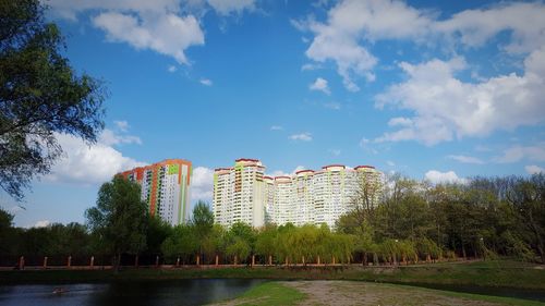 View of buildings by lake against cloudy sky