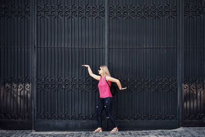 Full length of woman dancing against metal wall outdoors