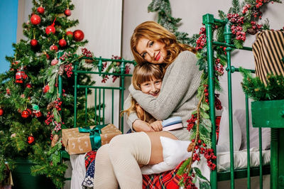 Mother hugging her little daughter in christmas decorated room.