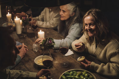 Smiling senior woman eating cupcake while talking to friend during party