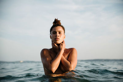 Portrait of shirtless young woman swimming in sea against sky