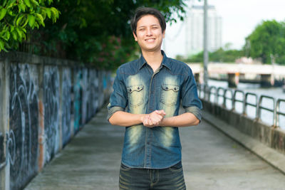 Portrait of young man standing against railing