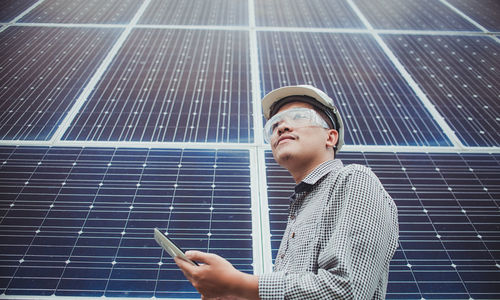 Low angle view of engineer using digital tablet with solar panels in background