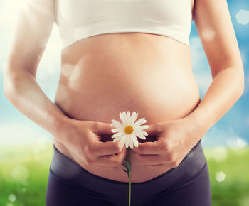 Midsection of woman standing by flowering plant