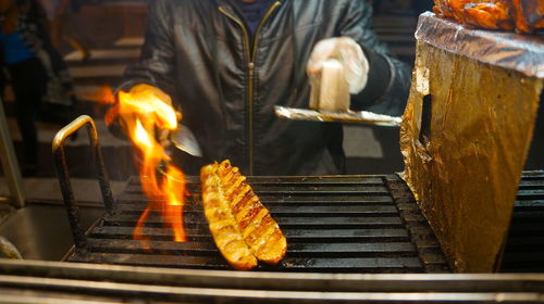 Midsection of person grilling meat on barbecue grill