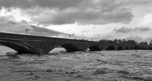 Arch bridge over river against sky