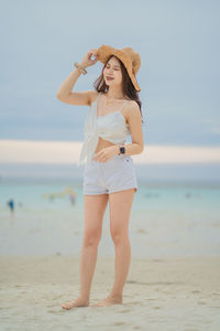 Full length of woman standing at beach against sky