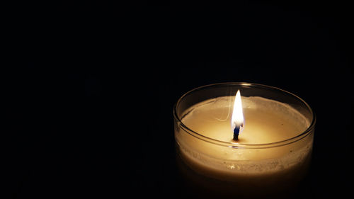 Close-up of lit candle against black background