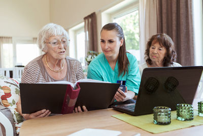 Nurse and senior women reading file while buying medicine online at nursing home