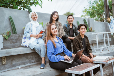 Friends using mobile phone while sitting on steps