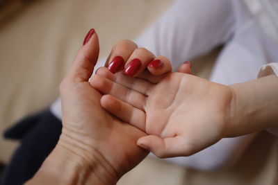 Close-up of mother holding hand of daughter