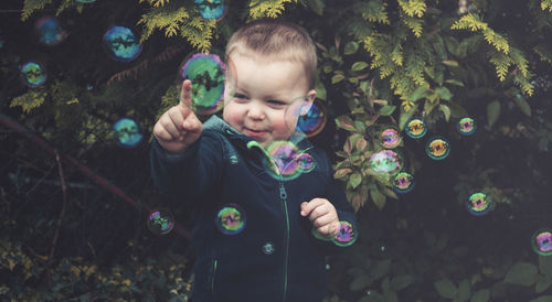 Cute boy playing with bubbles in plants