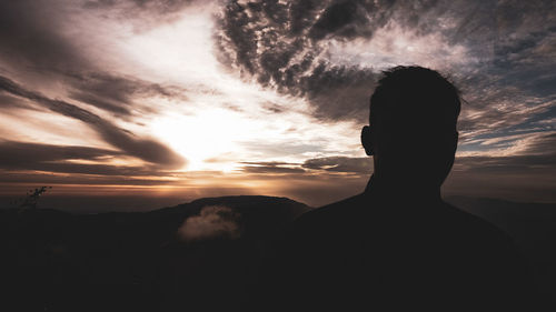 Silhouette man against cloudy sky during sunset