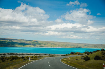 Empty road by sea against sky