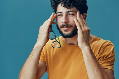 Portrait of young woman with headphones against blue background