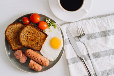 Breakfast plate with cup of black coffee, grilled sausage and whole wheat toast